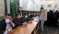 Iranian election officials wear masks as they wait for voters during parliamentary elections at the Shah Abdul Azim shrine on the southern outskirts of Tehran on February 21, 2020./ AFP / ATTA KENARE