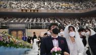 Couples wearing protective face masks attend a mass wedding ceremony organised by the Unification Church at Cheongshim Peace World Center in Gapyeong on February 7, 2020. AFP / Jung Yeon-je