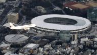 An aerial view shows an airplane flying near National Stadium in a test of the new flight paths for international passenger aircraft bound for Haneda Airport, in Tokyo, Japan February 2, 2020. Credit:  Kyodo/via Reuters  