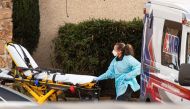 SEATTLE, WA - FEBRUARY 29: A healthcare worker prepares to transport a patient on a stretcher into an ambulance at Life Care Center of Kirkland in Kirkland, Washington. David Ryder/AFP
