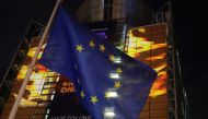 The European Union flag flies in front of images projected by activists from the environmental group Greenpeace showing Earth on fire onto the European Commission headquarters during a protest action on the eve of the presentation of the European Union cl