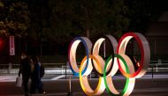  A couple wearing protective face masks, following the outbreak of the coronavirus, walk past The Olympic rings in front of the Japan Olympics Museum in Tokyo, Japan, March 3, 2020. REUTERS/Athit Perawongmetha 