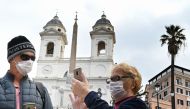 Tourists wearing protective masks looks on at Spanish Steps (Piazza di Spagna) in Rome on March 7, 2020 amid fear of Covid-19 epidemic. AFP / Alberto PIZZOLI