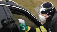A Czech police officer, with a protective mask, checks the temperature of a driver during sanitary checks on drivers at the border crossing between Germany and Czech Republic, near the German village of Furth and the Czech village Nova Kubice in a measure
