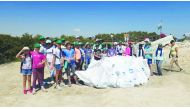 Volunteers pose after cleaning the mangrove forests at the Purple Island in Al Thakira.