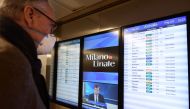 A passenger wearing a protective mask checks a flights timetable at Milan's Linate airport on March 11, 2020, a day after Italy imposed unprecedented national restrictions on its 60 million people Tuesday to control the deadly COVID-19 coronavirus. / AFP 