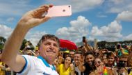 Brazilian President Jair Bolsonaro takes a selfie with supporters in front of the Planalto Palace, after a protest against the National Congress and the Supreme Court, in Brasilia, on March 15, 2020. / AFP / Sergio LIMA 