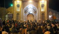 People gather outside the closed doors of the Fatima Masumeh shrine in Iran's holy city of Qom on March 16 2020. AFP / MEHDI MARIZAD