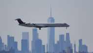 (FILES) In this file photo taken on March 15, 2020 A plane from Delta airline is seen above the skyline of Manhattan before it lands at JFK airport in New York City. AFP / Johannes EISELE
