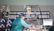 A medical worker wearing a protective mask and suit treats a patient suffering from coronavirus disease (COVID-19) in an intensive care unit at the Oglio Po hospital in Cremona, Italy March 19, 2020. (REUTERS/Flavio Lo Scalzo)