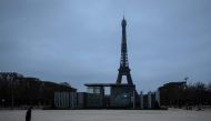 A man walks his dog at the Champs de mars on March 21, 2020 in Paris as a strict lockdown comes into in effect in France to stop the spread of COVID-19, caused by the novel coronavirus. AFP / JOEL SAGET
