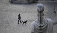 :A woman with her dog is seen crossing the deserted Piazza del Popolo while the Italians stay at home as part of a lockdown against the spread of coronavirus disease (COVID-19) in Rome, Italy March 22, 2020. REUTERS/Alberto Lingria