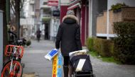 A woman carting toilet paper and kitchen rolls walks along a largely deserted Uhlandstrasse in Berlin on March 19, 2020. / AFP / Odd ANDERSEN