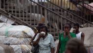 Residents protect their faces with masks and other items as a preventive measure against COVID-19 Coronavirus as city worker disinfects a market n Accra on March 23, 2020.   AFP / Nipah Dennis
