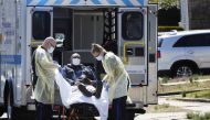 Emergency Medical Technicians (EMT) lift a patient that was identified to have coronavirus disease (COVID-19) into an ambulance while wearing protective gear, as the outbreak of coronavirus disease (COVID-19) continues, in New York City, New York, U.S., M
