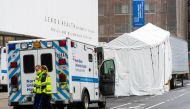 Paramedics walk next to a makeshift morgue set outside Lenox Health Medical Pavilion as the coronavirus disease (COVID-19) outbreak continues in New York, U.S., March 29, 2020. REUTERS/Eduardo Munoz
