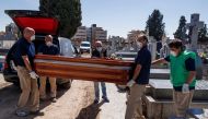 Mortuary employees wearing face masks carry the coffin of a COVID-19 coronavirus victim during a burial at the Fuencarral cemetery in Madrid on March 29, 2020. AFP / Baldesca Samper
  