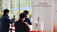 People take pictures in front of the Olympic Flame which was passed from Tokyo 2020 to Fukushima Prefecture at the J-Village National Training Centre in Naraha on April 2, 2020. / AFP / Kazuhiro NOGI
