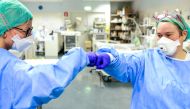 TOPSHOT - Members of the medical staff give themselves a fist bump while working at the intensive care unit (ICU) with the COVID-19 patients at the ASST Papa Giovanni XXIII hospital in Bergamo, on April 3, 2020. / AFP / Piero CRUCIATTI