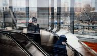 Men wearing face masks ride down an escalator at Nizhegorodskaya station of the Moscow Central Ring, a commuter rail line circling the city, in Moscow on April 8, 2020, during the strict lockdown in Russia to stop the spread of the novel coronavirus COVID