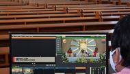 A man tends to a live broadcast of clergy conducting Easter mass in an empty church and streamed online as part of social distancing measures amidst the COVID-19 coronavirus pandemic in Jakarta on April 12, 2020. AFP / ADEK BERRY