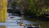 People paddle inflatable boats along the Landwehr canal in Berlin's Kreuzberg district as the sun shines on Easter Sunday, April 12, 2020 amid the novel coronavirus COVID-19 pandemic. / AFP / David GANNON