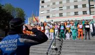 :TOPSHOT - A policeman salutes heathcare workers outside the Gregorio Maranon Hospital in Madrid on April 12, 2020, during a national lockdown to prevent the spread of the COVID-19 disease. Spain's daily death toll from the coronavirus rose to 619, after 