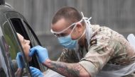 A member of the military tests a person at a coronavirus test centre in the car park of Chessington World of Adventures as the spread of the coronavirus disease (COVID-19) continues, Chessington, Britain, London, Britain, April 18, 2020. REUTERS/Toby Melv