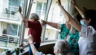 Staff members and residents salute their families at the elderly residence Christalain on April 17, 2020, in Brussels, during a strict lockdown in the country to fight against the novel coronavirus. / AFP / kenzo tribouillard