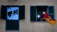 People wave an AS Roma flag at their windows as they listen to artists performing in the courtyard of a popular apartment building for the show Sotto lo Stesso Cielo tour (Under the Same Sky tour) in San Basilio suburbs of Rome on April 18, 2020, during t
