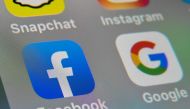(FILES) This file picture taken on October 1, 2019 shows the logos of mobile apps Facebook and Google displayed on a tablet in Lille. Australia announced on April 20, 2020 it will begin forcing Google and Facebook to pay news companies for content, in a l