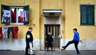 TOPSHOT - Children wearing protective face masks play football in front of their building in rome's neighbourhood of San Basilio on April 18, 2020, during the country's lockdown aimed at stopping the spread of the novel coronavirus COVID-19. / AFP / Alber