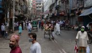 People walk on an empty street usually busy with stalls selling traditional food for Iftar, the breaking fast of Muslim's holy fasting month of Ramadan, during a government-imposed lockdown as a preventative measure against the spread of the COVID-19 coro