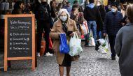 A woman wearing a protective facemask walks in the Aligre street as she does her grocery shopping during the food market, on May 2, 2020, in Paris, during the 47th day of a strict lockdown in France aimed at curbing the spread of the COVID-19 (the novel c