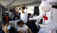 A member of the Red Cross takes the temperature of passengers of a bus as a preventive measure against the spread of the novel coronavirus, COVID-19, on the Guadalajara-Morelia highway, Jalisco State, Mexico, on May 2, 2020. / AFP / ULISES RUIZ