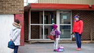 Students line up to have their hands sanitized in the schoolyard, as schools outside the greater Montreal region begin to reopen their doors amid the coronavirus disease (COVID-19) outbreak, in Saint-Jean-sur-Richelieu, Quebec, Canada May 11, 2020. REUTER