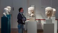 A visitor checks out roman busts at the Altes Museum (Old Museum) in Berlin on May 12, 2020, after the museum re-opened its doors to the public following a relaxation of lockdown restrictions due to the new coronavirus COVID-19 pandemic. / AFP / John MACD