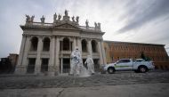 Employees of a disinfecting services company, wearing protective overalls and mask, sprays sanitizer on the forecourt during the sanitation of the Archbasilica of Saint John Lateran (San Giovanni in Laterano) in Rome on May 15, 2020  AFP / Filippo MONTEFO
