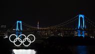 The Olympic rings, the Rainbow Bridge and the Tokyo Tower are seen at night in Tokyo on May 15, 2020. / AFP / CHARLY TRIBALLEAU