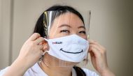 :An employee puts on a mask and a face shield at the Siam Paragon shopping mall as it reopened after restrictions to halt the spread of the COVID-19 coronavirus were lifted in Bangkok on May 17, 2020. / AFP / Mladen ANTONOV
