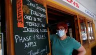 Toni, 45, owner of a pub in Magaluf beach wearing face mask and gloves poses next to a board with the rules to be applied during the reopening of commercial activity after the coronavirus disease (COVID-19) outbreak in Palma de Mallorca, in Mallorca Spain