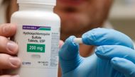 A pharmacy tech holds a bottle and a pill of Hydroxychloroquine at Rock Canyon Pharmacy in Provo, Utah, on May 20, 2020. US President Donald Trump announced May 18 he has been taking hydroxychloroquine for almost two weeks as a preventative measure agains