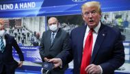 U.S. President Donald Trump holds a protective face mask with a presidential seal on it that he said he had been wearing earlier in his tour as Ford Motor Company CEO Jim Hackett looks on at the Ford Rawsonville Components Plant that is manufacturing vent
