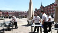 Workers use measuring tape to check social distancing as they set up a terrace which will be allowed to open from May 25, amid the coronavirus disease (COVID-19) outbreak, at Plaza Mayor Square in Madrid, Spain, May 24, 2020. REUTERS/Sergio Perez