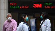 Traders wearing masks arrive before the opening bell at the New York Stock Exchange (NYSE) on May 26, 2020 at Wall Street in New York City. AFP / Johannes EISELE
