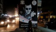 FILE PHOTO: A woman walks past a poster depicting Syria's President Bashar al-Assad in Damascus, Syria, March 5, 2020. REUTERS/Yamam Al Shaar/File Photo