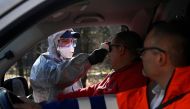 FILE PHOTO: A police officer in a protective suit checks the temperature of a person inside a car at Slovak-Czech border in Drietoma crossing, Slovakia, March 13, 2020. REUTERS/Radovan Stoklasa
