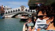 Tourists wear face masks as they pass the Rialto Bridge on a vaporetto (water taxi), amid the coronavirus disease (COVID-19) outbreak, in Venice, Italy June 21, 2020. REUTERS/Fabrizio Bensch