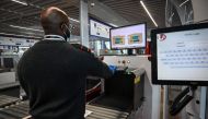 An airport staff member check passengers' luggage passing through X-ray machine at the Terminal 3 of the Orly airport, in Orly on the outskirts of Paris, on June 22, 2020 a few days before its reopening. AFP / BERTRAND GUAY