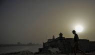 A man walks near Morro Castle as a vast cloud of Sahara dust is blanketing the city of Havana on June 24, 2020.  AFP / YAMIL LAGE